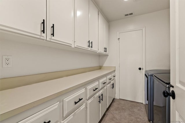 clothes washing area with cabinets, separate washer and dryer, and light tile patterned flooring