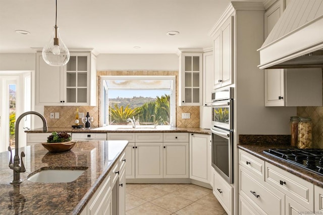 kitchen featuring dark stone countertops, custom range hood, gas cooktop, and sink