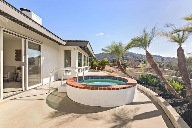 view of patio featuring a mountain view and an in ground hot tub