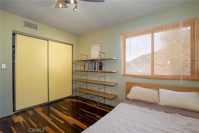 bedroom featuring ceiling fan, a closet, and dark hardwood / wood-style flooring