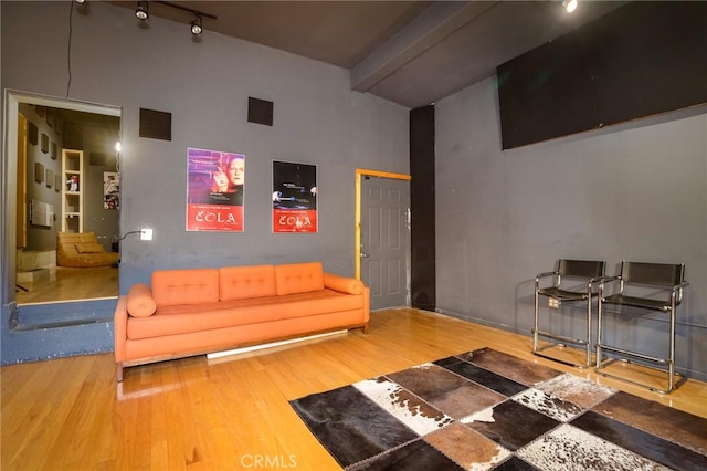 living room with track lighting, wood-type flooring, and beamed ceiling