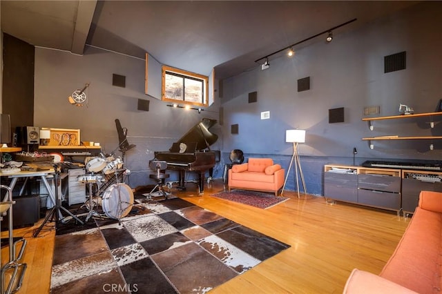 living room with a high ceiling, rail lighting, and hardwood / wood-style floors