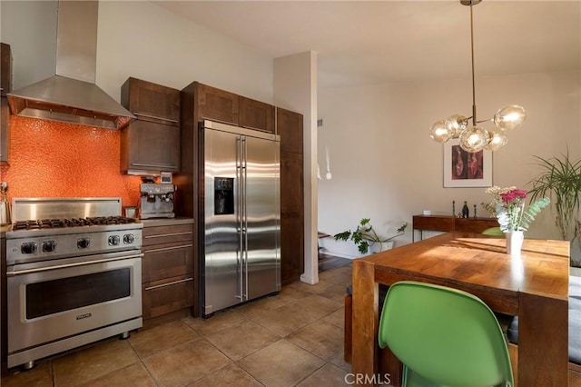 kitchen with pendant lighting, high end appliances, ventilation hood, butcher block countertops, and light tile patterned floors