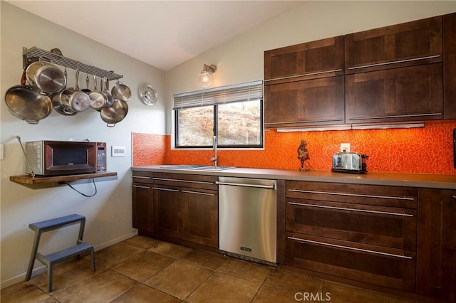 kitchen with appliances with stainless steel finishes, tasteful backsplash, vaulted ceiling, dark tile patterned floors, and sink