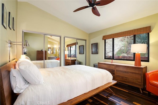 bedroom with lofted ceiling, ceiling fan, dark hardwood / wood-style flooring, and two closets