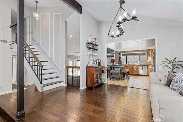 living room with sink, wood-type flooring, vaulted ceiling, and an inviting chandelier