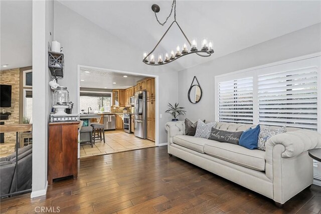 living room featuring light hardwood / wood-style floors, sink, and vaulted ceiling