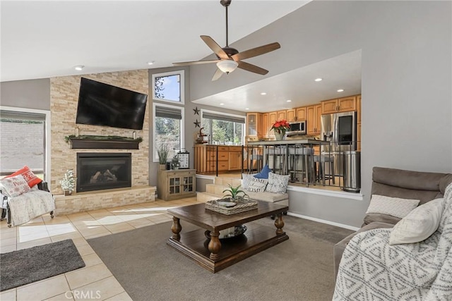 tiled living room featuring lofted ceiling, ceiling fan, and a fireplace