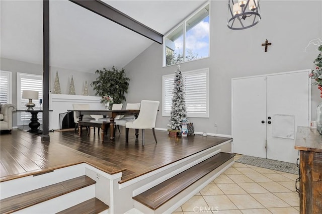 tiled entrance foyer featuring high vaulted ceiling, plenty of natural light, beamed ceiling, and an inviting chandelier