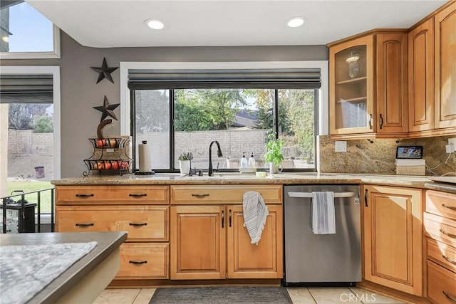 kitchen with light tile patterned flooring, a healthy amount of sunlight, stainless steel dishwasher, and backsplash