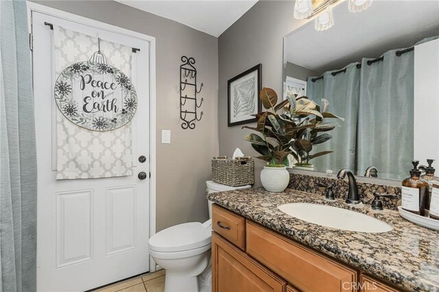 bathroom with toilet, vanity, and tile patterned floors