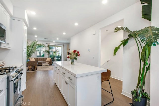 kitchen featuring a breakfast bar area, a kitchen island, gas stove, and white cabinetry