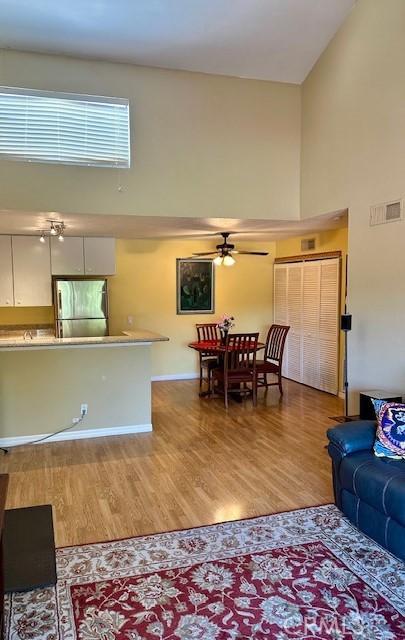 living room featuring a high ceiling, ceiling fan, and hardwood / wood-style flooring