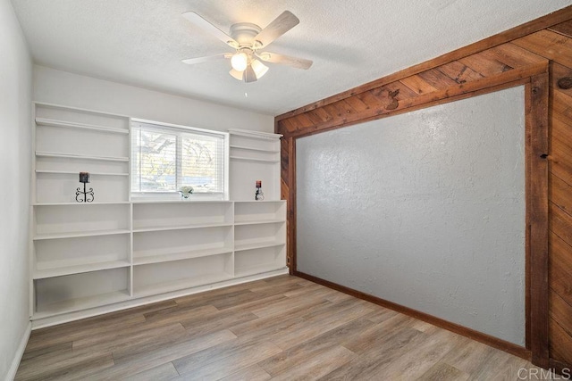 empty room featuring ceiling fan, wood-type flooring, and a textured ceiling