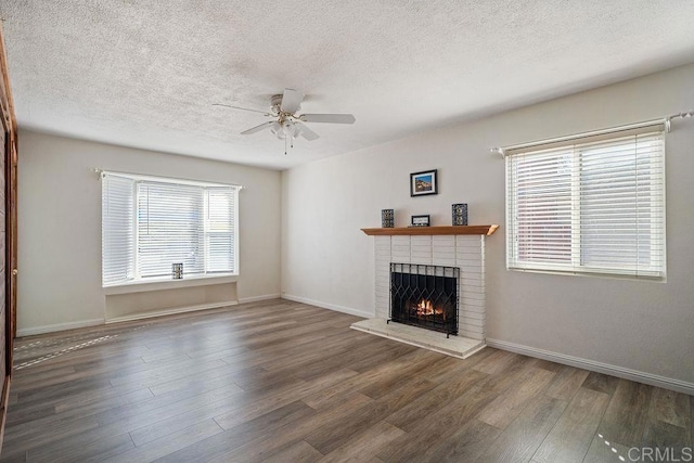 unfurnished living room featuring ceiling fan, a fireplace, and dark wood-type flooring