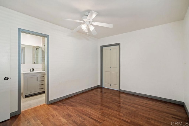 unfurnished bedroom with ensuite bathroom, ceiling fan, sink, wood-type flooring, and a closet