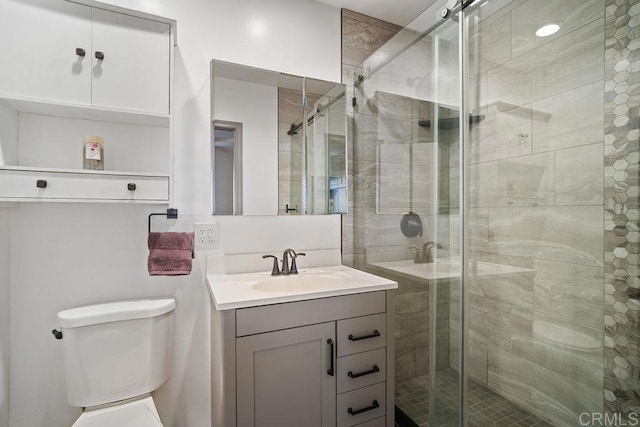 bathroom with vanity, toilet, and a shower with door