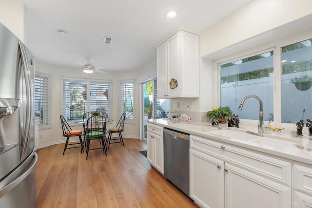 kitchen featuring light stone countertops, white cabinets, stainless steel appliances, sink, and ceiling fan