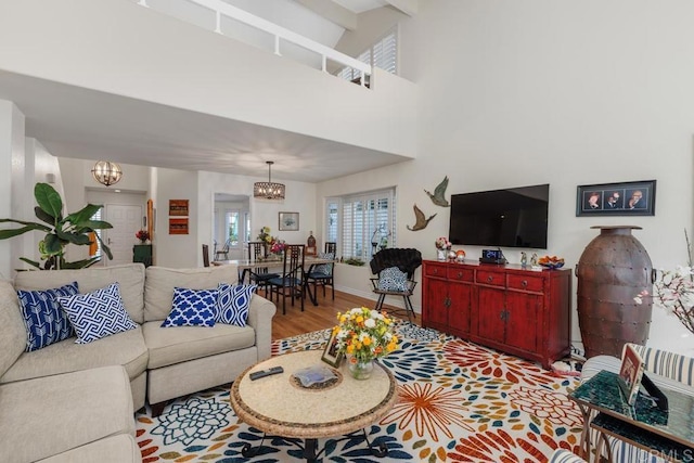 living room featuring an inviting chandelier, a towering ceiling, and light hardwood / wood-style flooring