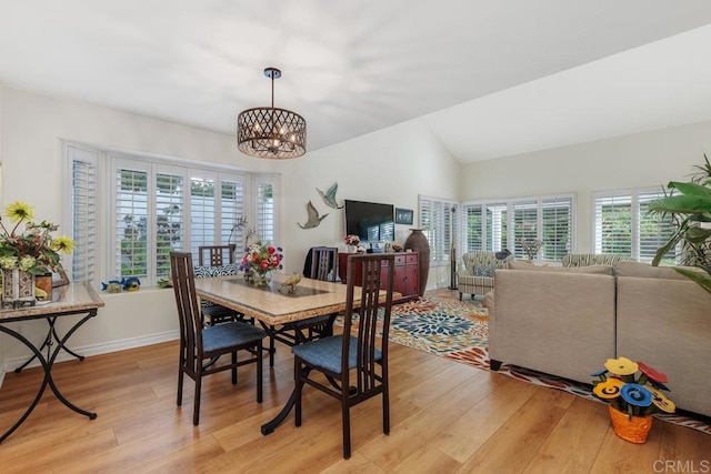 dining room with an inviting chandelier, lofted ceiling, and light hardwood / wood-style flooring