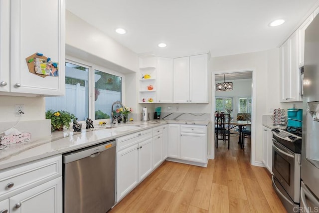 kitchen featuring an inviting chandelier, white cabinetry, stainless steel appliances, light wood-type flooring, and light stone counters