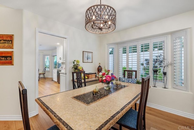 dining room featuring light wood-type flooring, plenty of natural light, and a notable chandelier