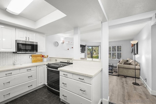 kitchen with tasteful backsplash, white cabinetry, light stone countertops, a textured ceiling, and black / electric stove