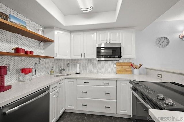 kitchen with tasteful backsplash, dark tile patterned flooring, sink, white cabinetry, and appliances with stainless steel finishes