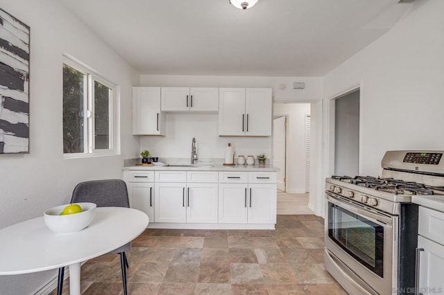 kitchen featuring white cabinets, stainless steel range with gas stovetop, and sink