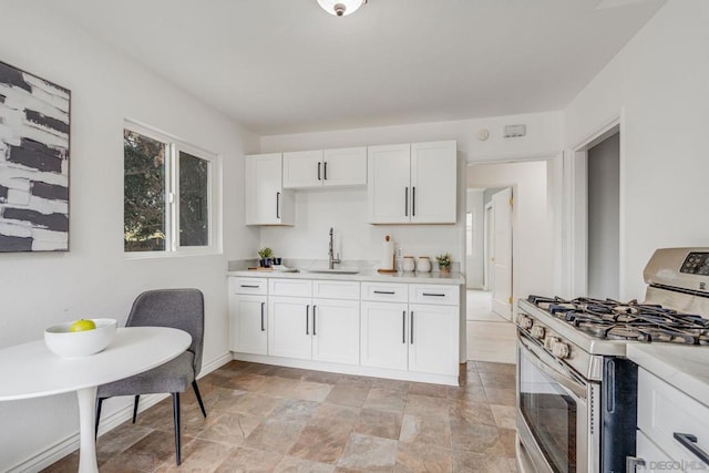 kitchen featuring stainless steel gas stove, sink, and white cabinetry