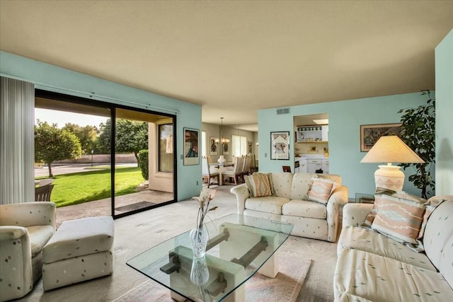 carpeted living room with a chandelier