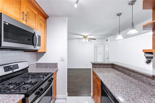 kitchen with hanging light fixtures, appliances with stainless steel finishes, ceiling fan, and tasteful backsplash