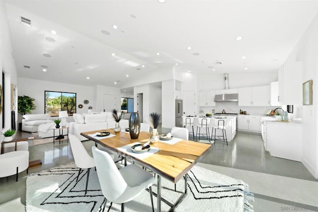 dining space featuring sink, concrete flooring, and vaulted ceiling