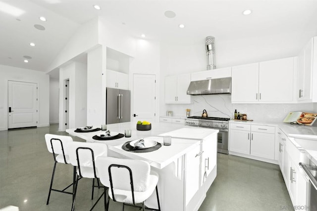 kitchen with a kitchen bar, tasteful backsplash, a kitchen island, high quality appliances, and white cabinets