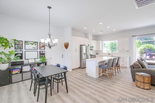 dining space with light wood-type flooring, a chandelier, and sink