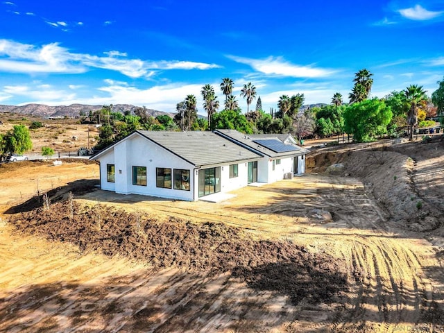 rear view of house featuring a mountain view and solar panels