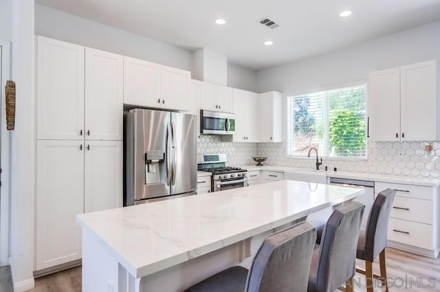 kitchen with a kitchen breakfast bar, white cabinetry, stainless steel appliances, and a kitchen island