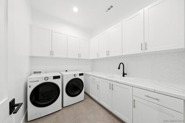 clothes washing area featuring washer and clothes dryer, sink, and cabinets