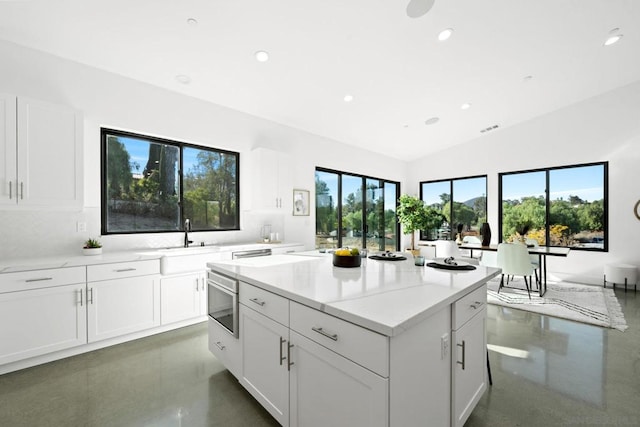 kitchen featuring lofted ceiling, sink, white cabinetry, built in microwave, and light stone countertops