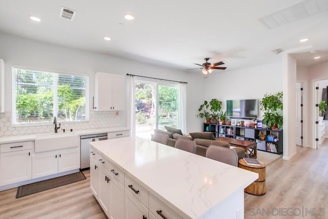 kitchen featuring stainless steel dishwasher, decorative backsplash, sink, and white cabinetry