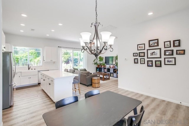 dining space featuring sink, a chandelier, and light hardwood / wood-style flooring