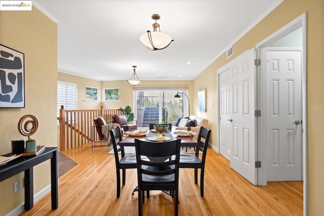 dining space with a healthy amount of sunlight, ornamental molding, and light hardwood / wood-style floors