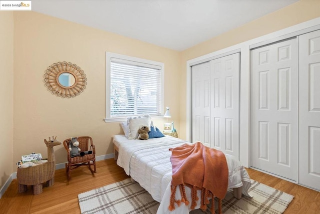 bedroom with light wood-type flooring and two closets