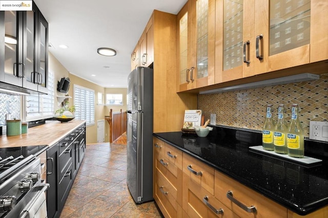 kitchen featuring dark tile patterned floors, backsplash, dark stone countertops, and stainless steel appliances