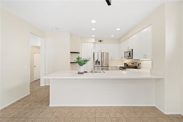 kitchen featuring white cabinetry, light tile patterned floors, kitchen peninsula, and appliances with stainless steel finishes