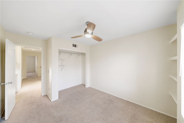 unfurnished bedroom featuring ceiling fan, light colored carpet, and a closet