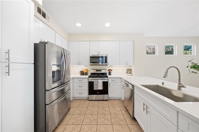 kitchen featuring light tile patterned flooring, appliances with stainless steel finishes, sink, and white cabinets