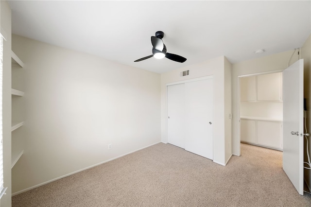 unfurnished bedroom featuring light colored carpet, a closet, and ceiling fan