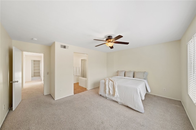 bedroom with light colored carpet, ceiling fan, and ensuite bathroom