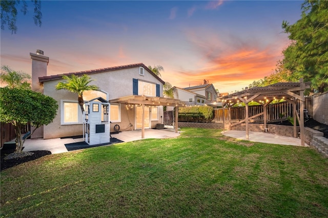 back house at dusk featuring a pergola, a patio, and a yard